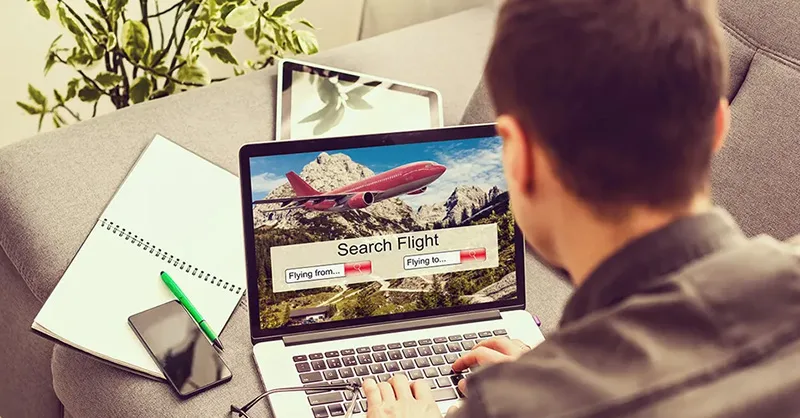 Image, photo d'une personne, un homme assise devant un ordinateur avec des onglets de sites de réservation ouverts, ou un billet d'avion en promo.