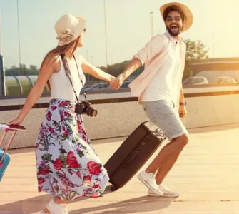 Voyage en amoureux : image, photo d'un coupe main dans la main, marchant au coucher du soleil avec leurs valises