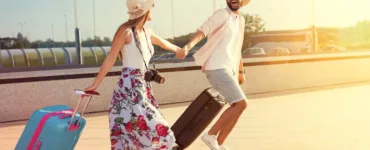 Voyage en amoureux : image, photo d'un coupe main dans la main, marchant au coucher du soleil avec leurs valises